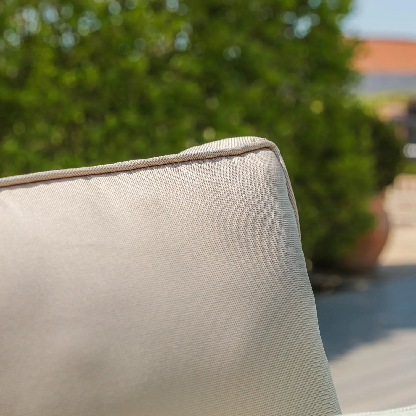 Beige outdoor furniture cushion with piped edge shown in close-up