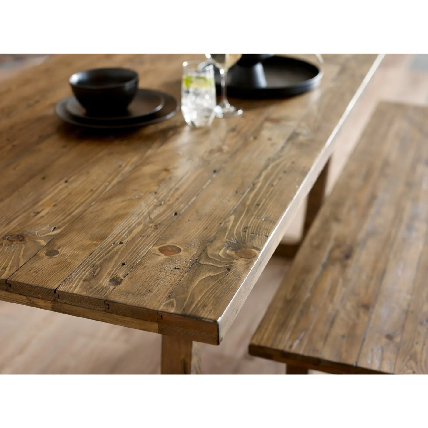 Rustic wooden dining table with bench, close-up view of grain and tableware