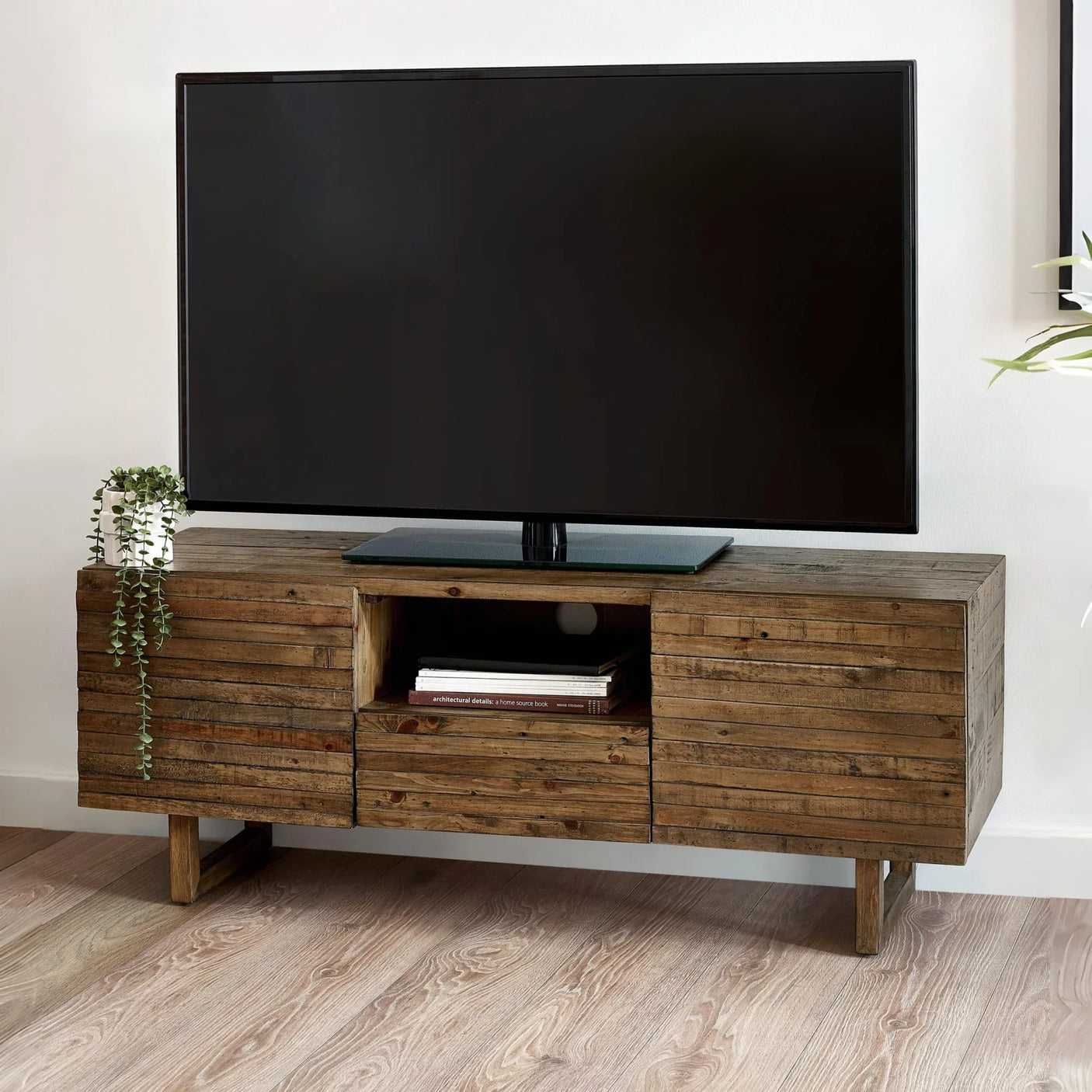 Rustic wooden TV stand with storage shelves, large flat screen TV, potted plant on top