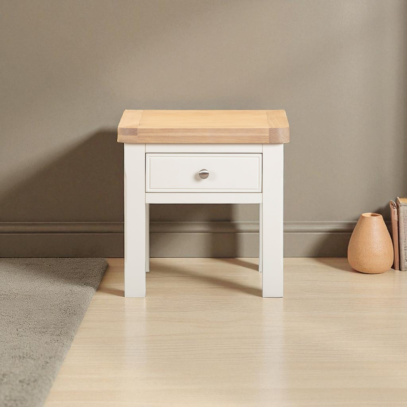 Small wooden side table with a white base against a beige wall.
