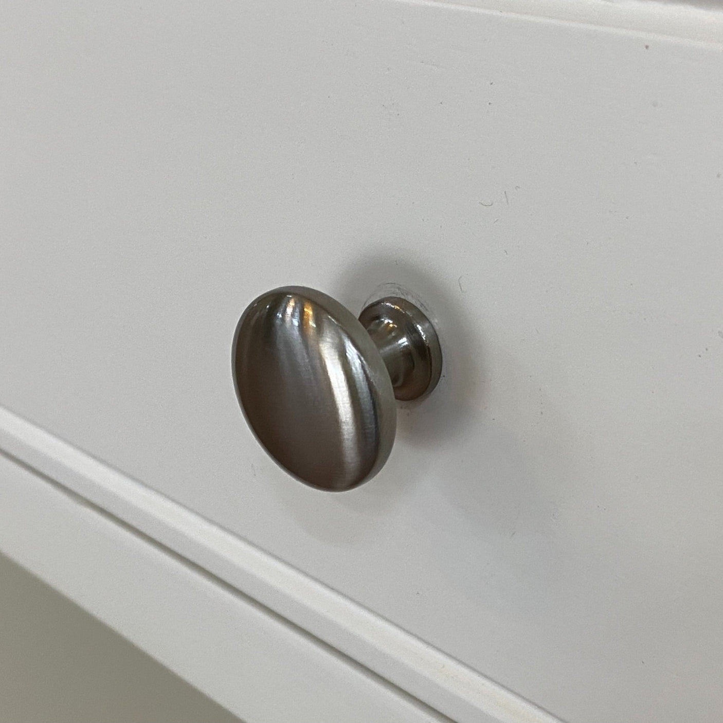 Metallic cabinet knob on a white cabinet door