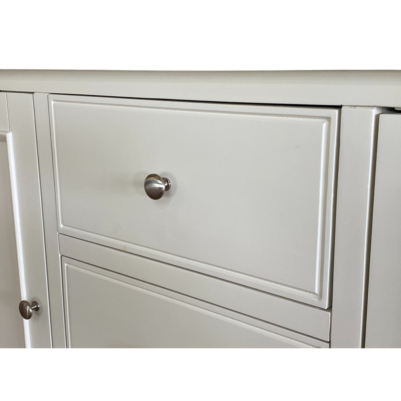 Close-up of a light gray cabinet with a silver handle on a white background