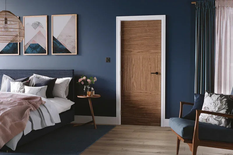 Walnut internal door with modern grain in a stylish bedroom featuring navy walls and contemporary decor