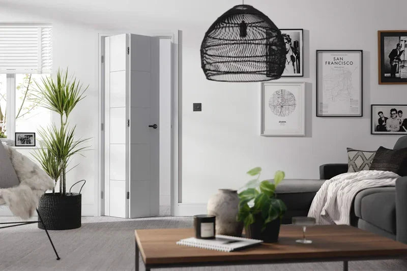 White Vancouver bi-fold door installed in modern living room with grey sofa and framed prints