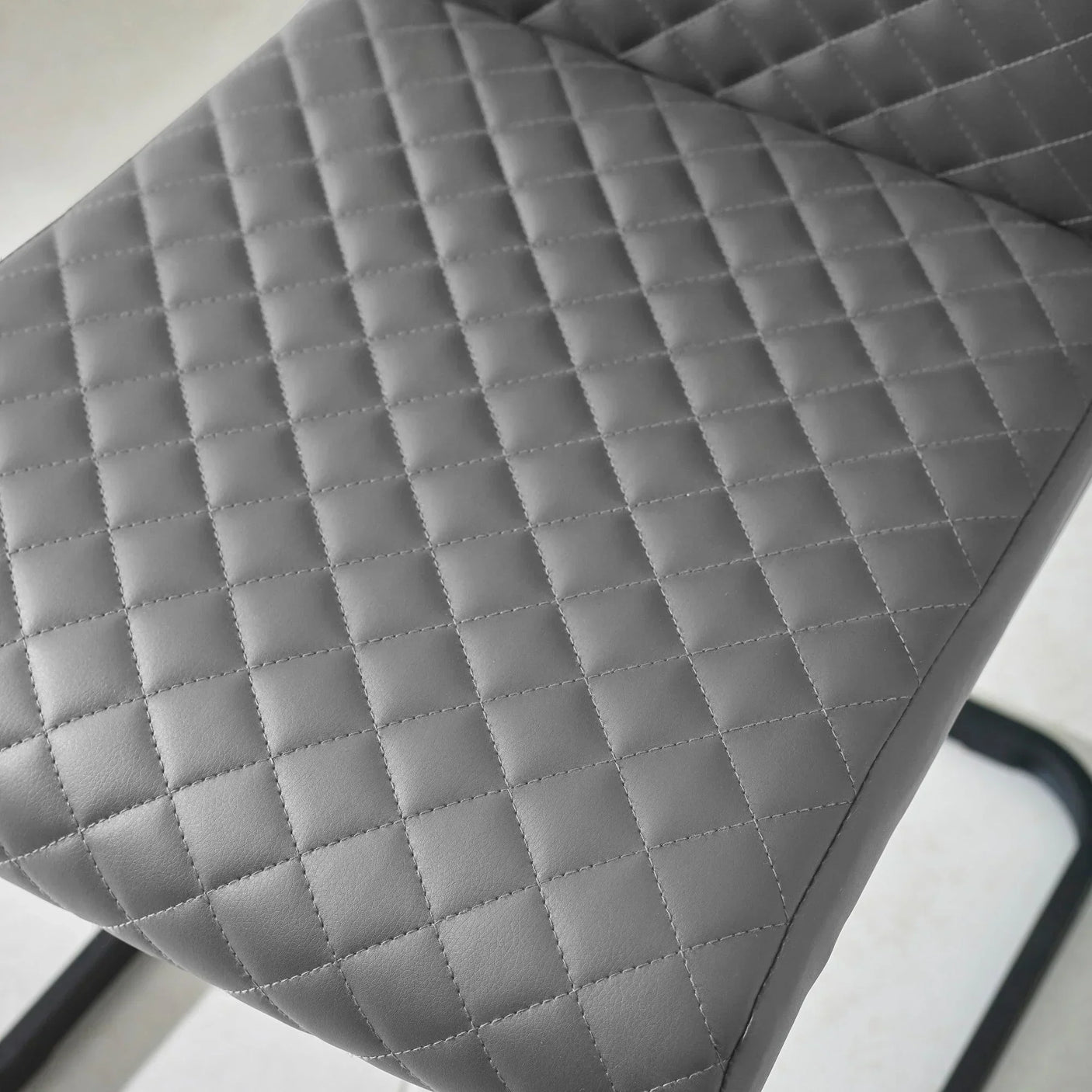 Close-up of grey quilted dining chair seat with diamond stitching pattern