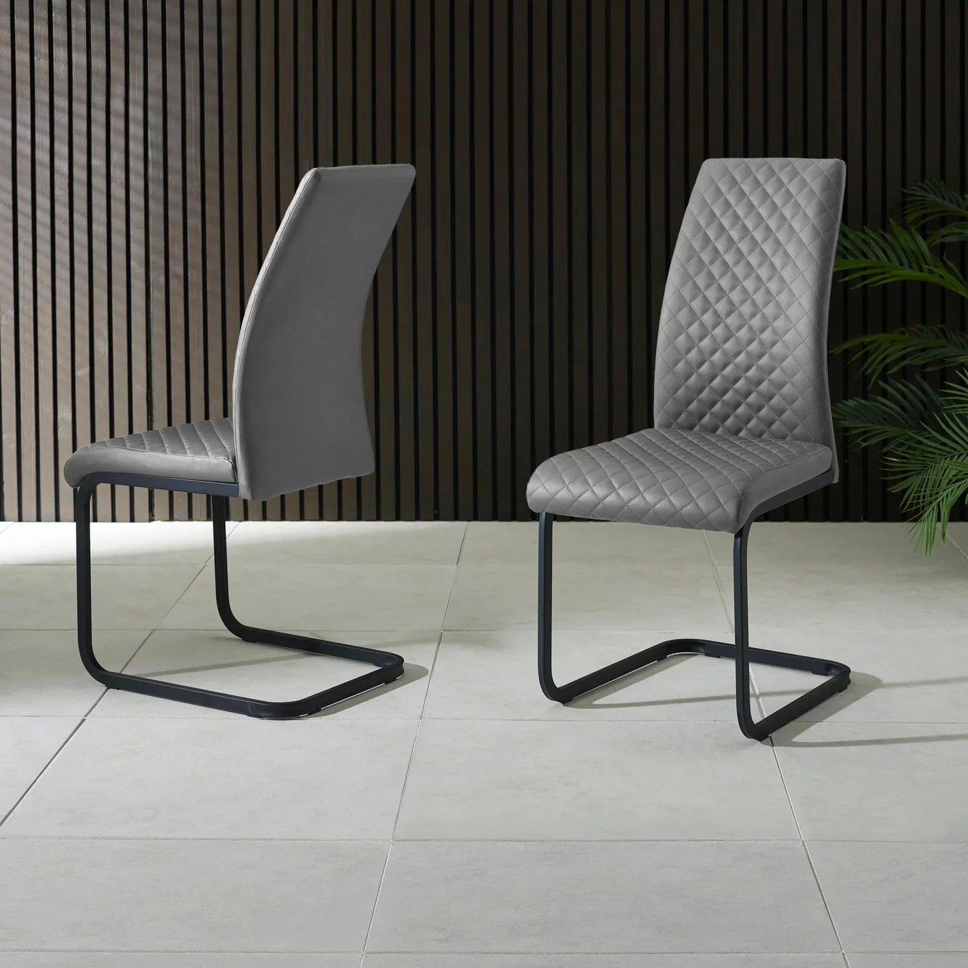 Pair of grey faux leather dining chairs with quilted backrest and black cantilever legs