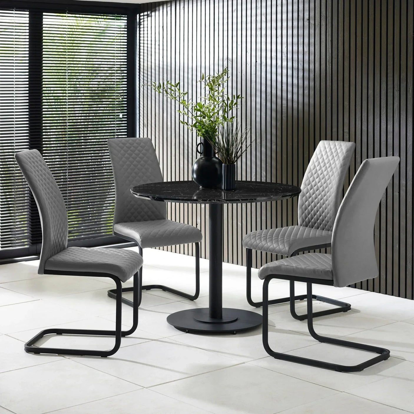 Modern grey dining table set with four quilted chairs and black pedestal base