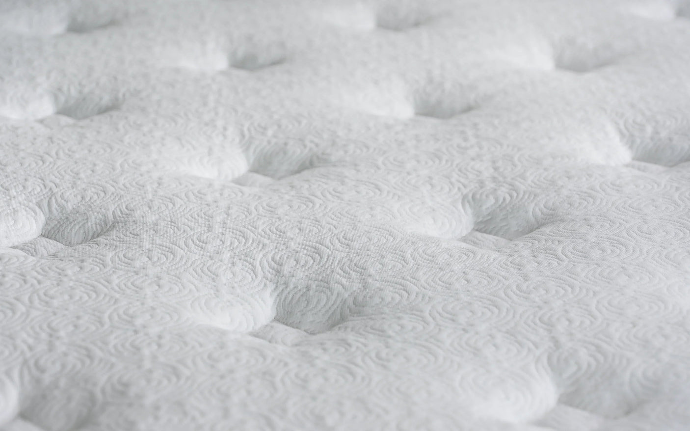 Closeup of white mattress surface with tufted pattern detail
