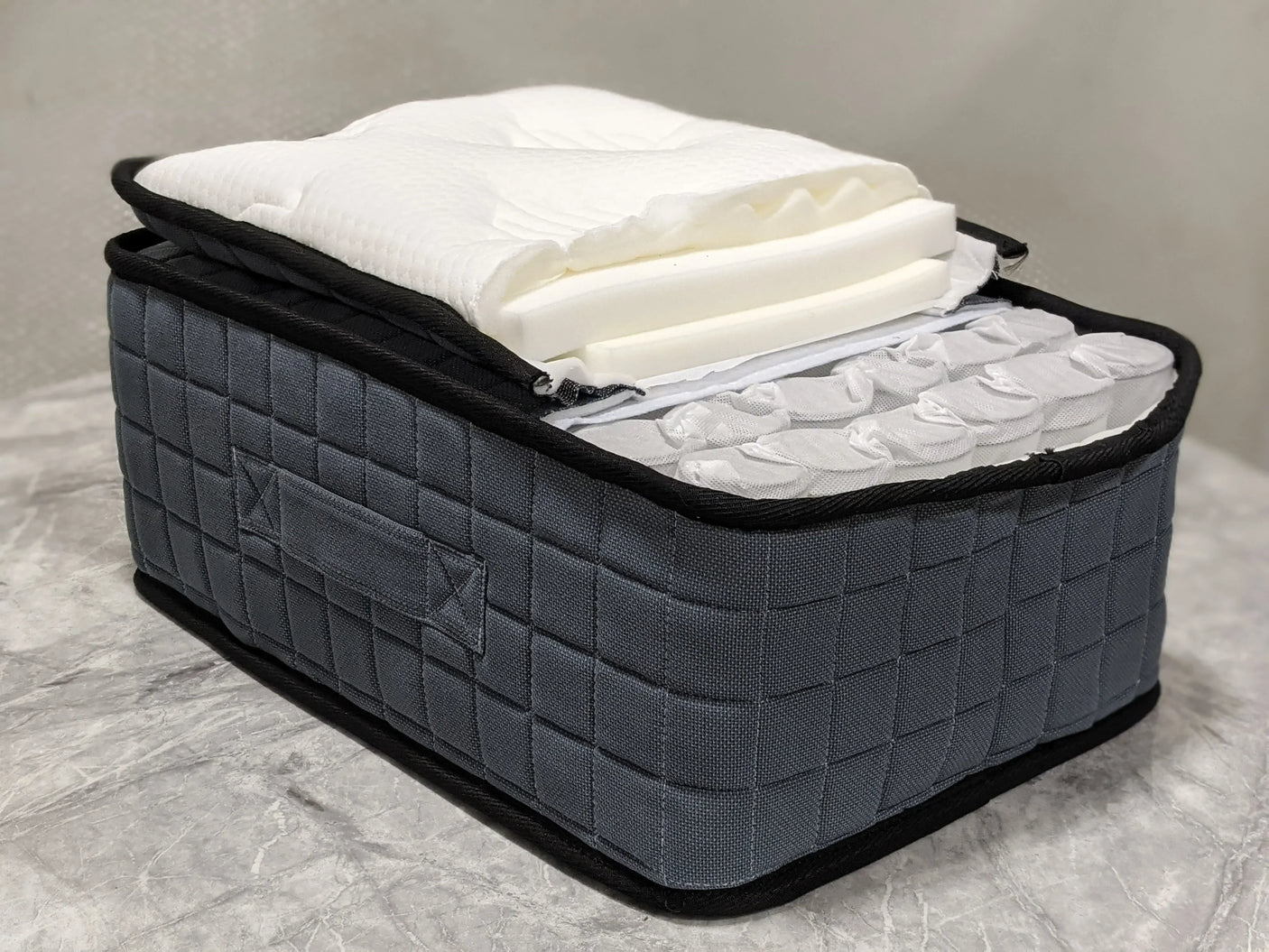 Pocket sprung mattress cross section showing grey quilted fabric and foam layers