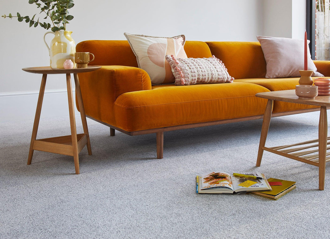 Mustard velvet sofa with pink and cream scatter cushions in modern living room setting