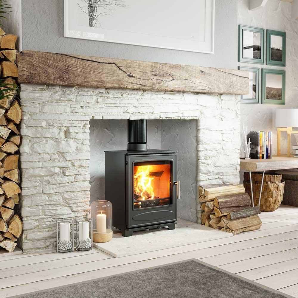 Wood burning stove in stone fireplace with stacked logs in modern living room
