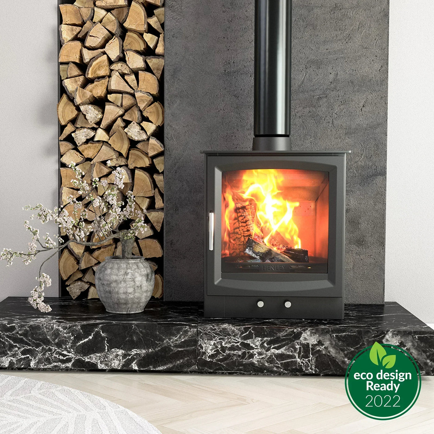 Modern wood burning stove with glass door on black marble hearth, firewood stacked beside