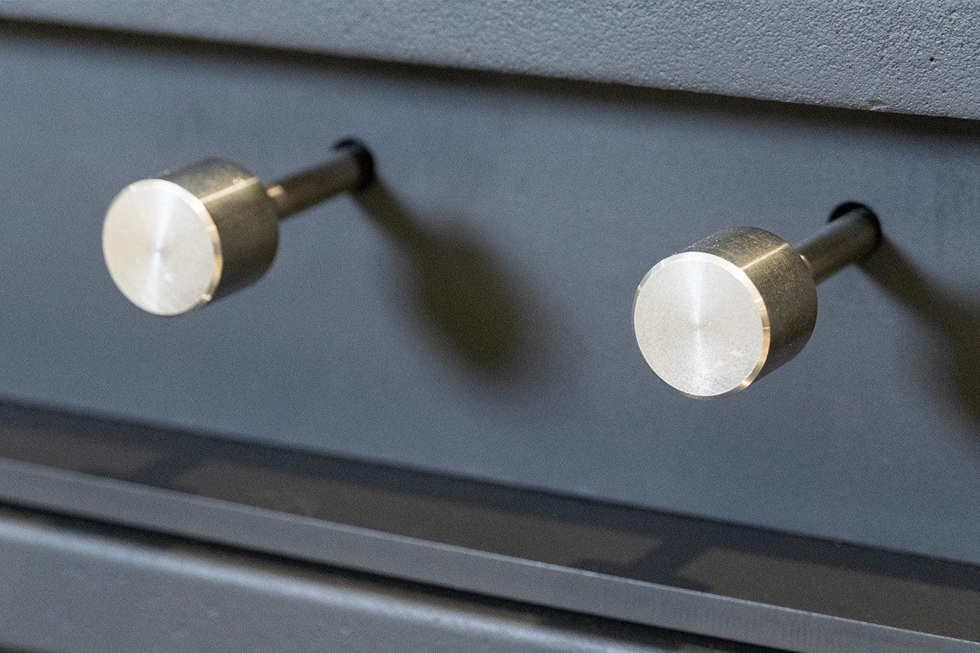 Brushed metal pull handles installed on dark cabinet drawer front