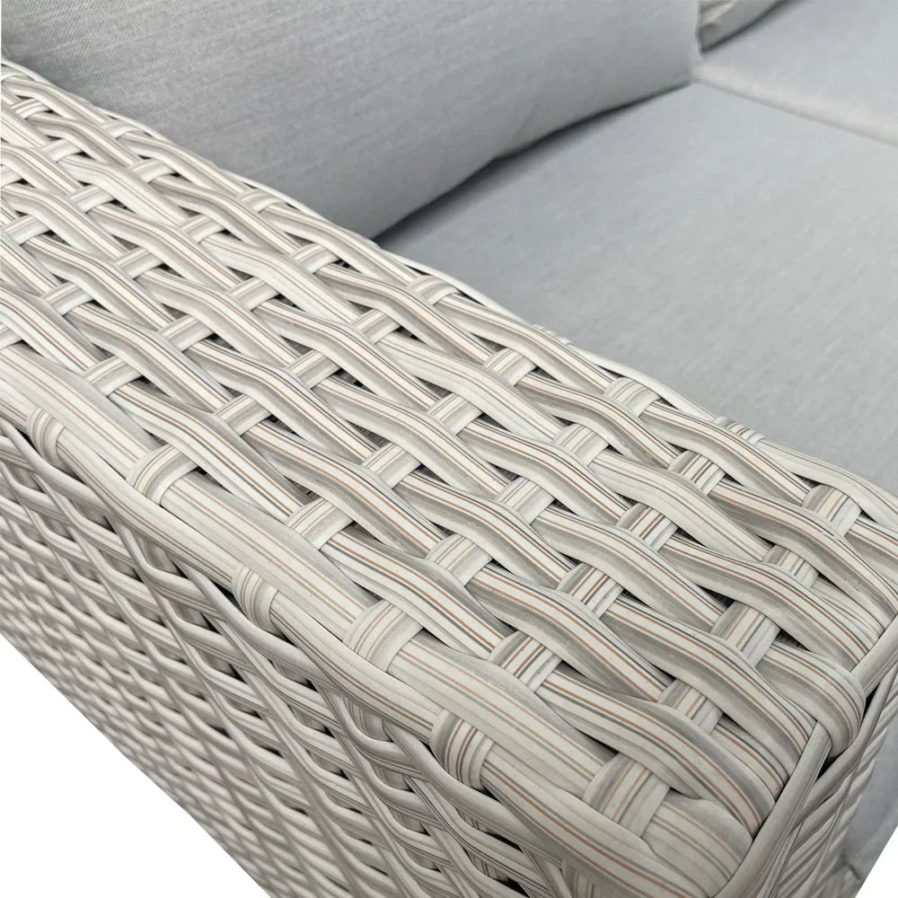 Grey rattan sofa armrest with woven detail and light cushioned seating