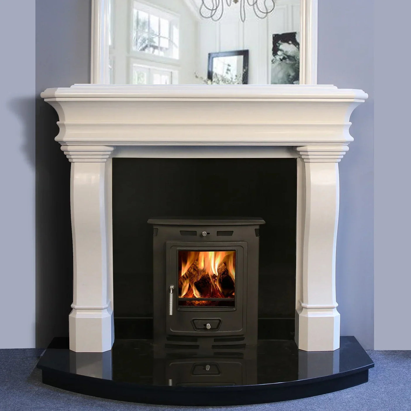 White fireplace surround with black wood burning stove and burning fire on black hearth