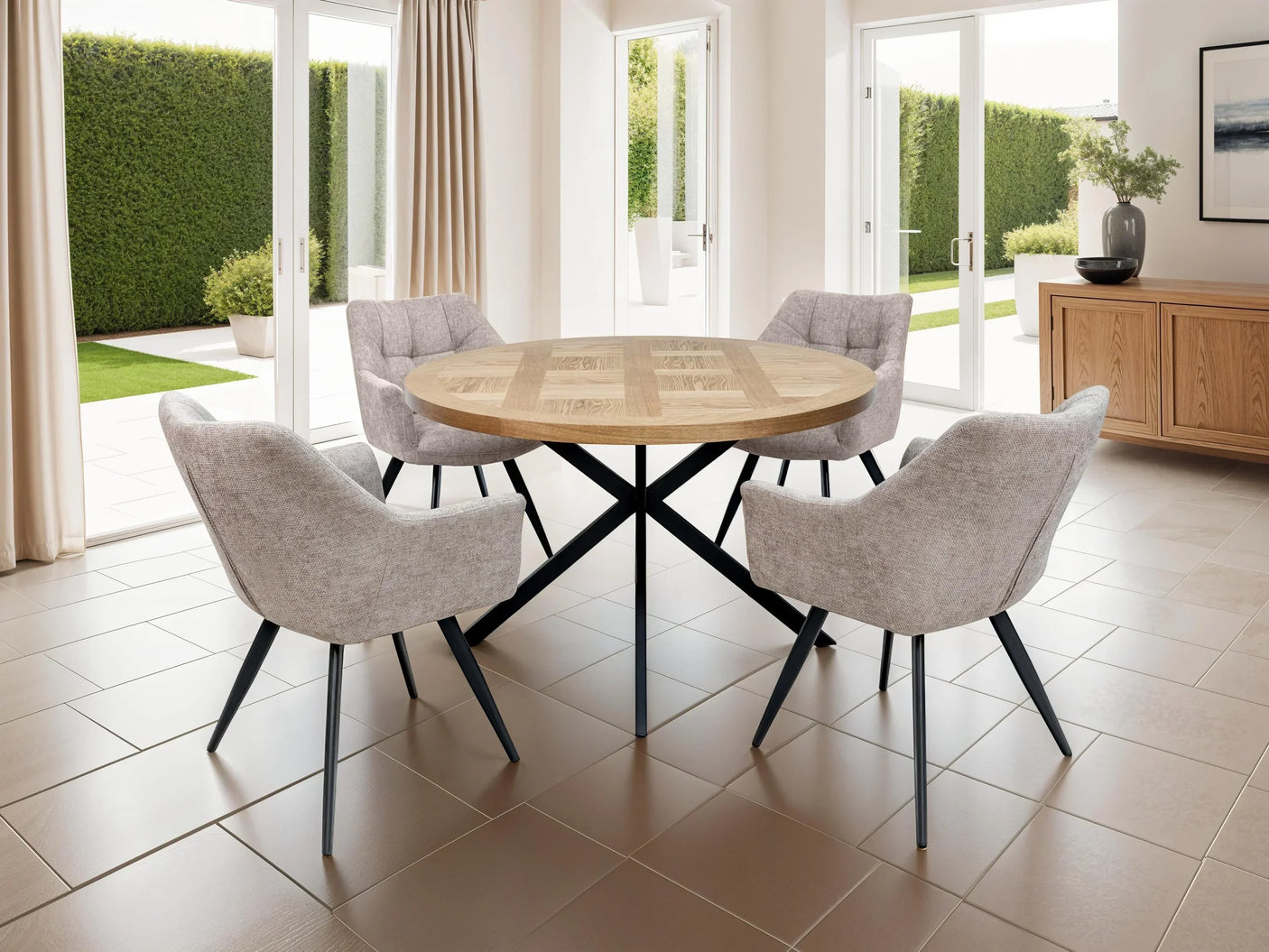 Round oak dining table with four grey fabric chairs in a bright modern room