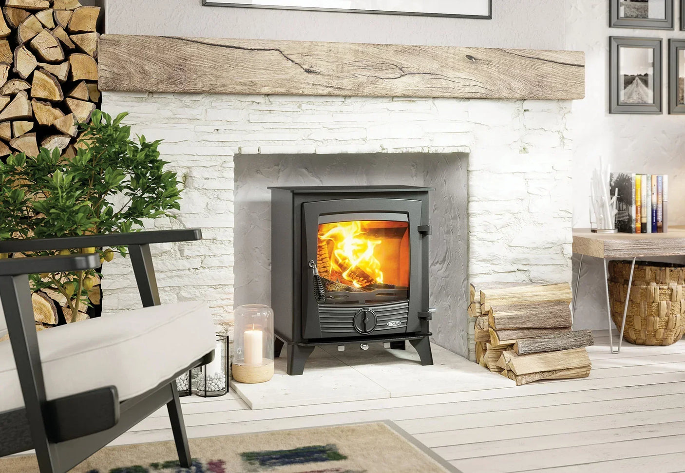 Black wood burning stove with fire inside set in white brick fireplace, logs and decor nearby