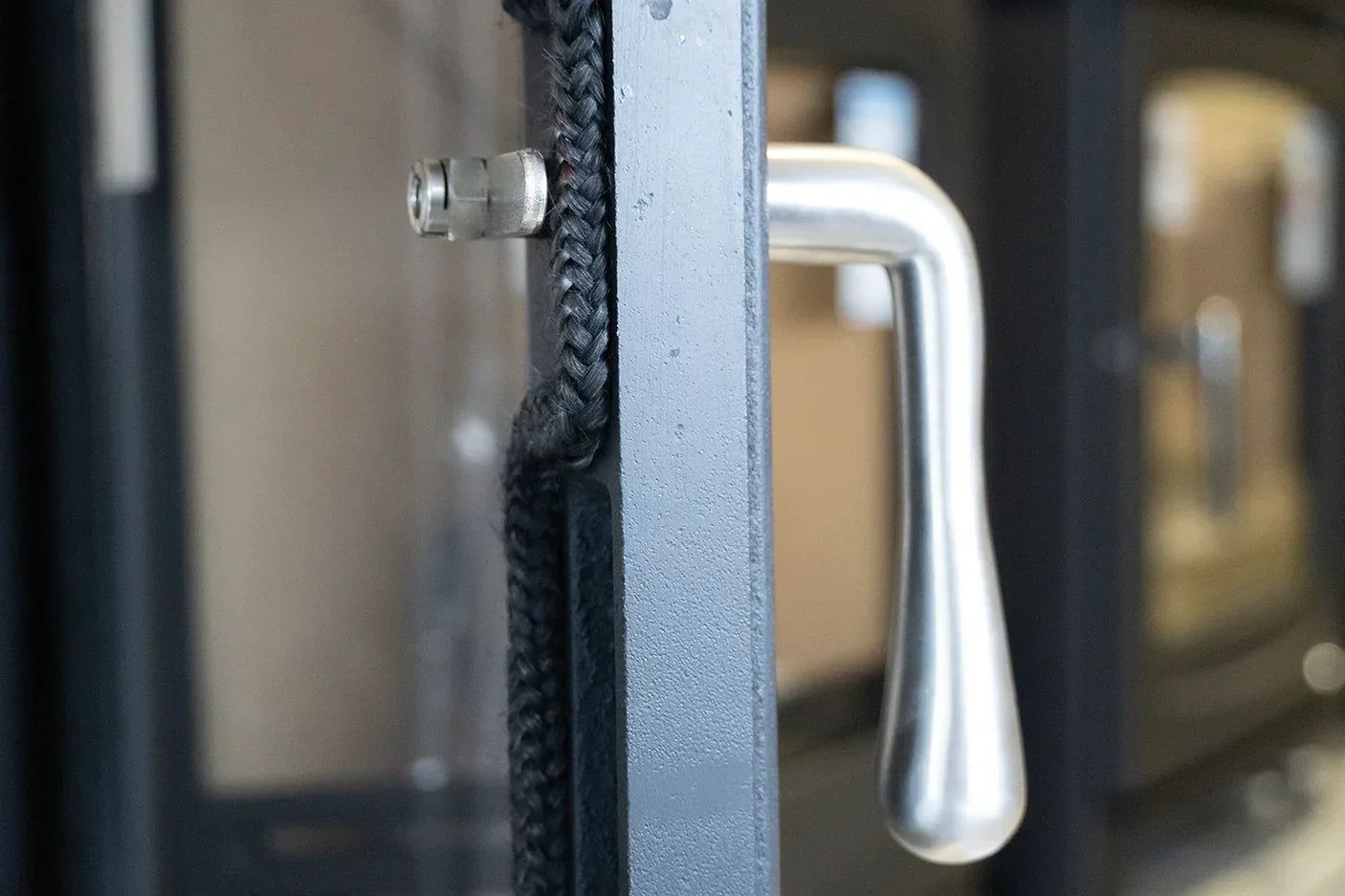 Stove door close-up with stainless steel handle and black heat-resistant rope seal