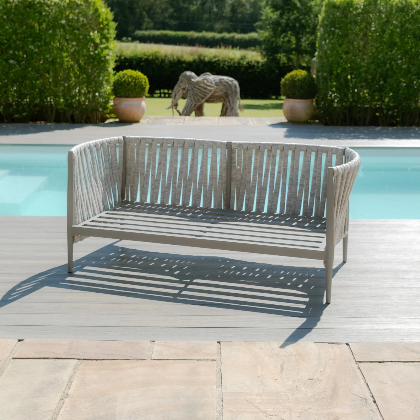 Light grey outdoor garden bench with slatted backrest by pool on patio