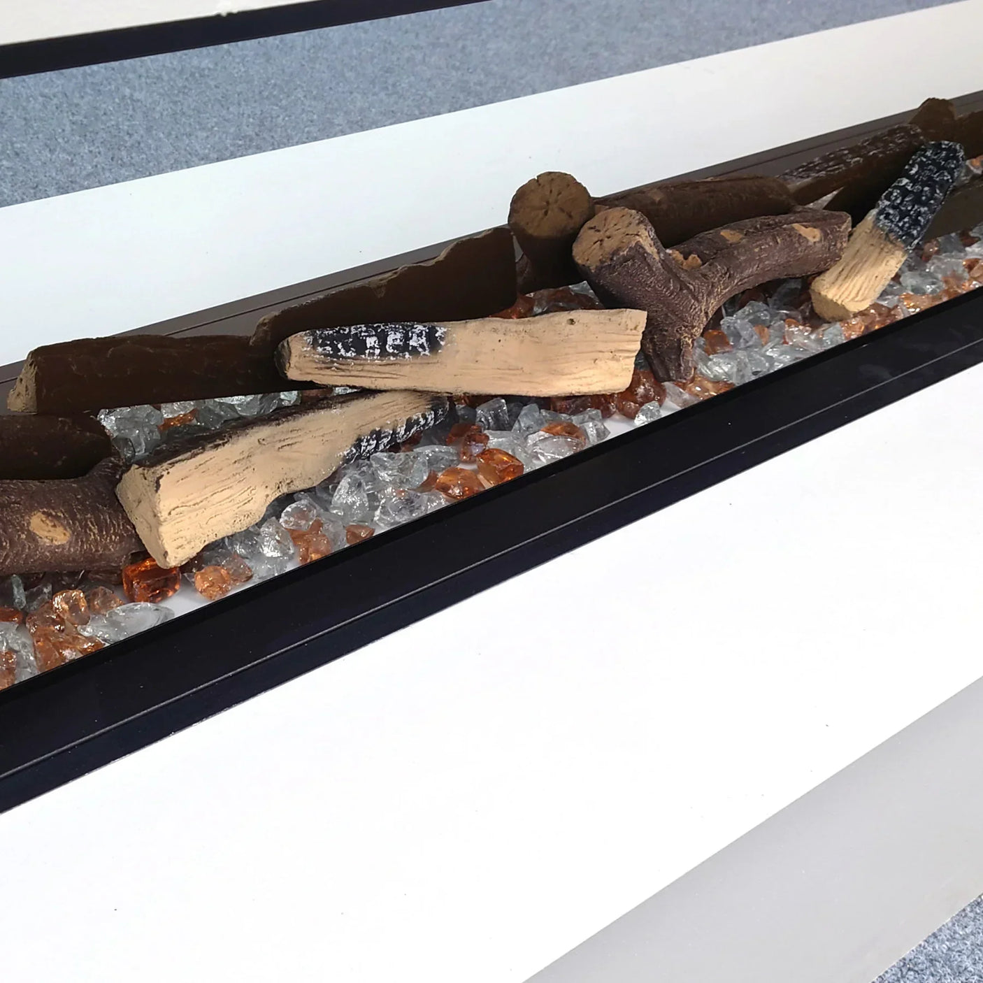 Modern fuel bed with ceramic logs and glass crystals in linear black fire grate