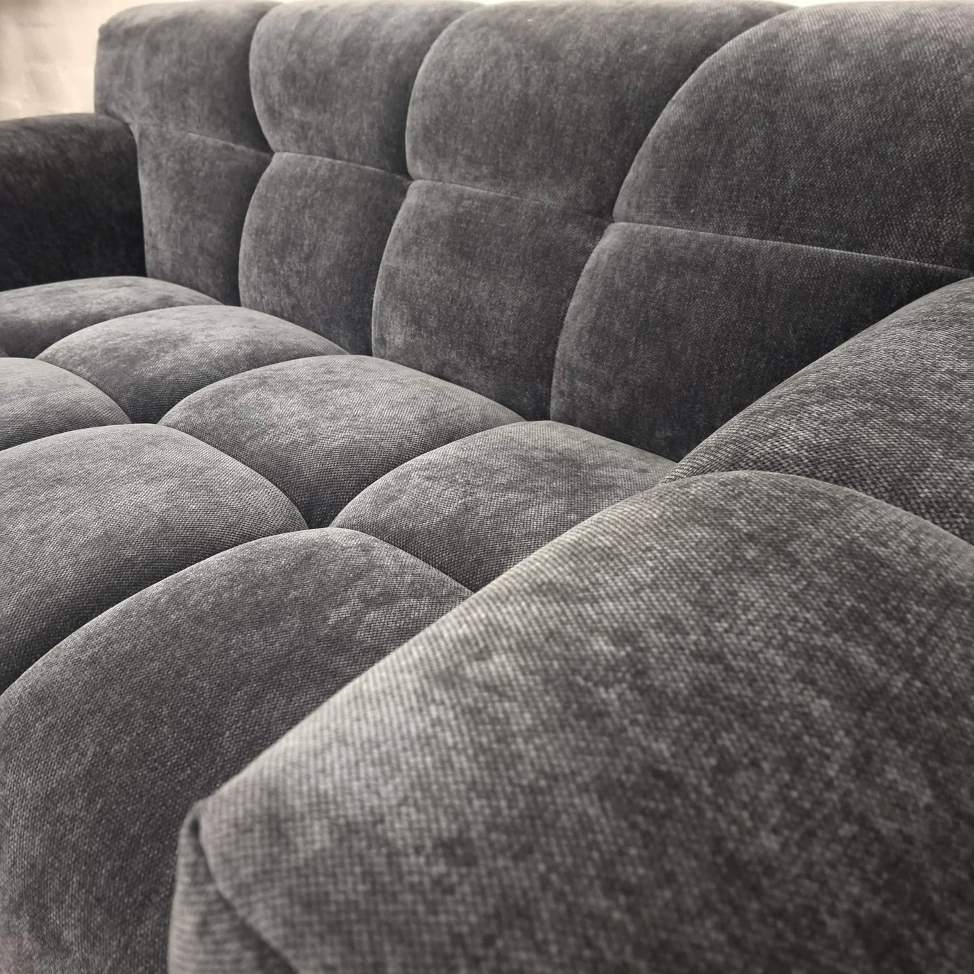 Close-up of grey fabric sofa upholstery with deep tufted cushions