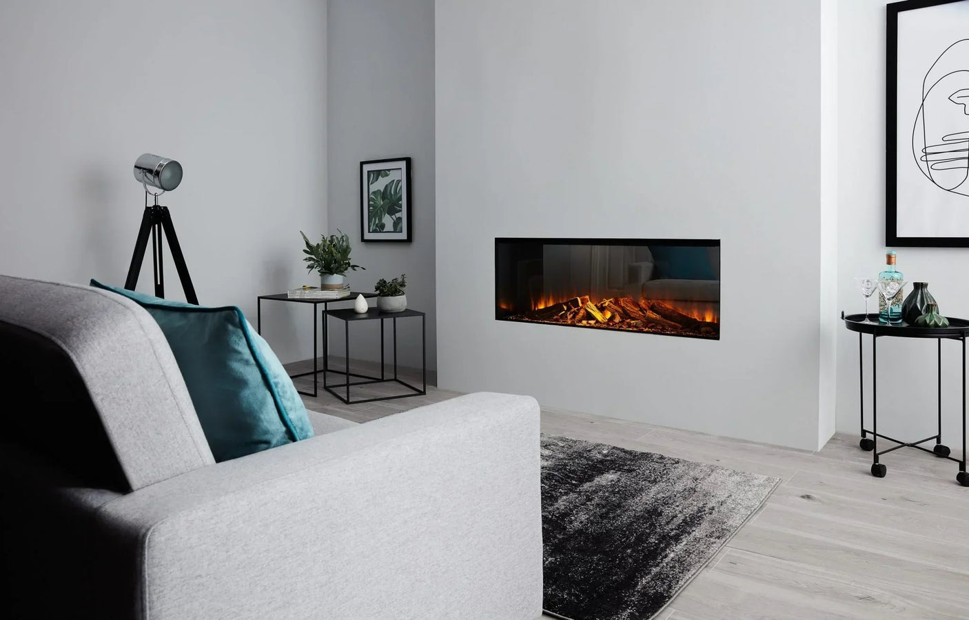 Modern living room with grey sofa, wall-mounted electric fireplace and black side tables