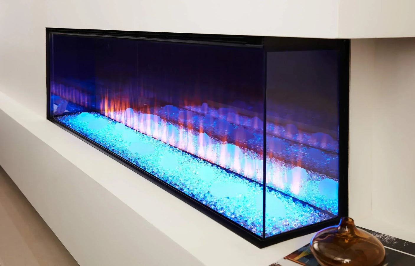 Modern electric fireplace with blue crystal bed and flame effect in white wall setting