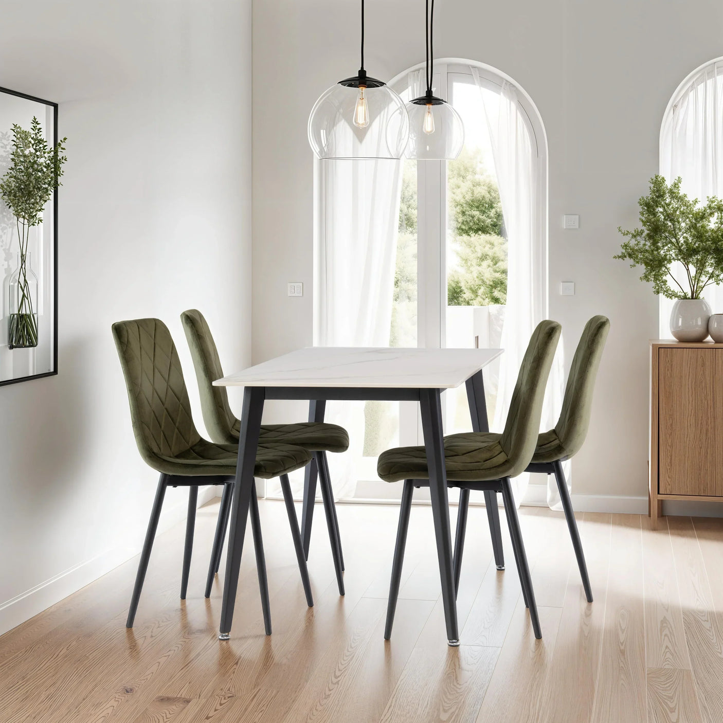 Modern dining table with white top and four green velvet chairs in bright dining room