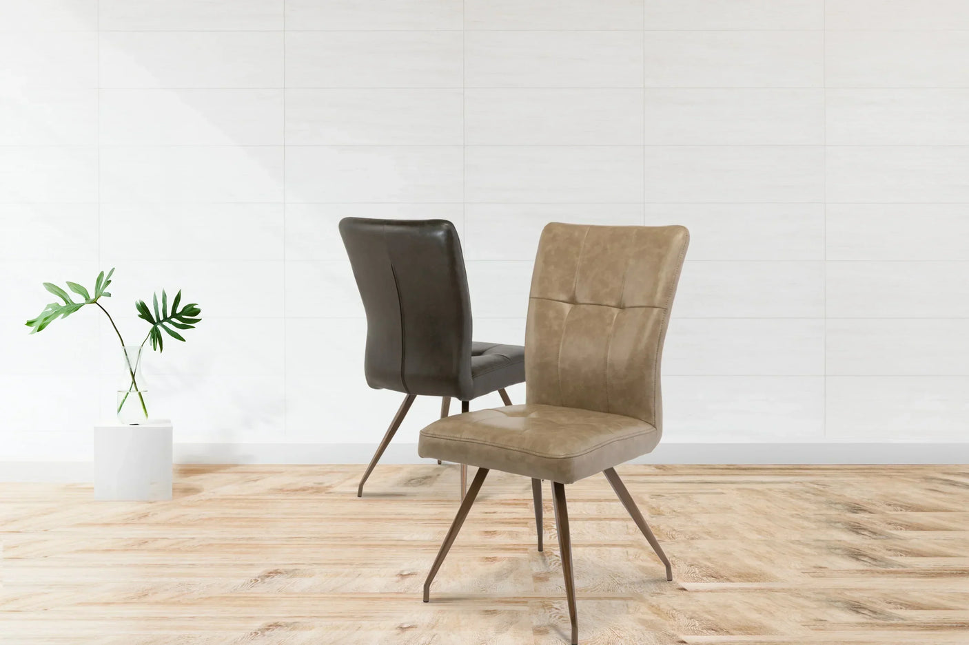 Pair of dining chairs with brass legs and padded neutral upholstery on wood floor