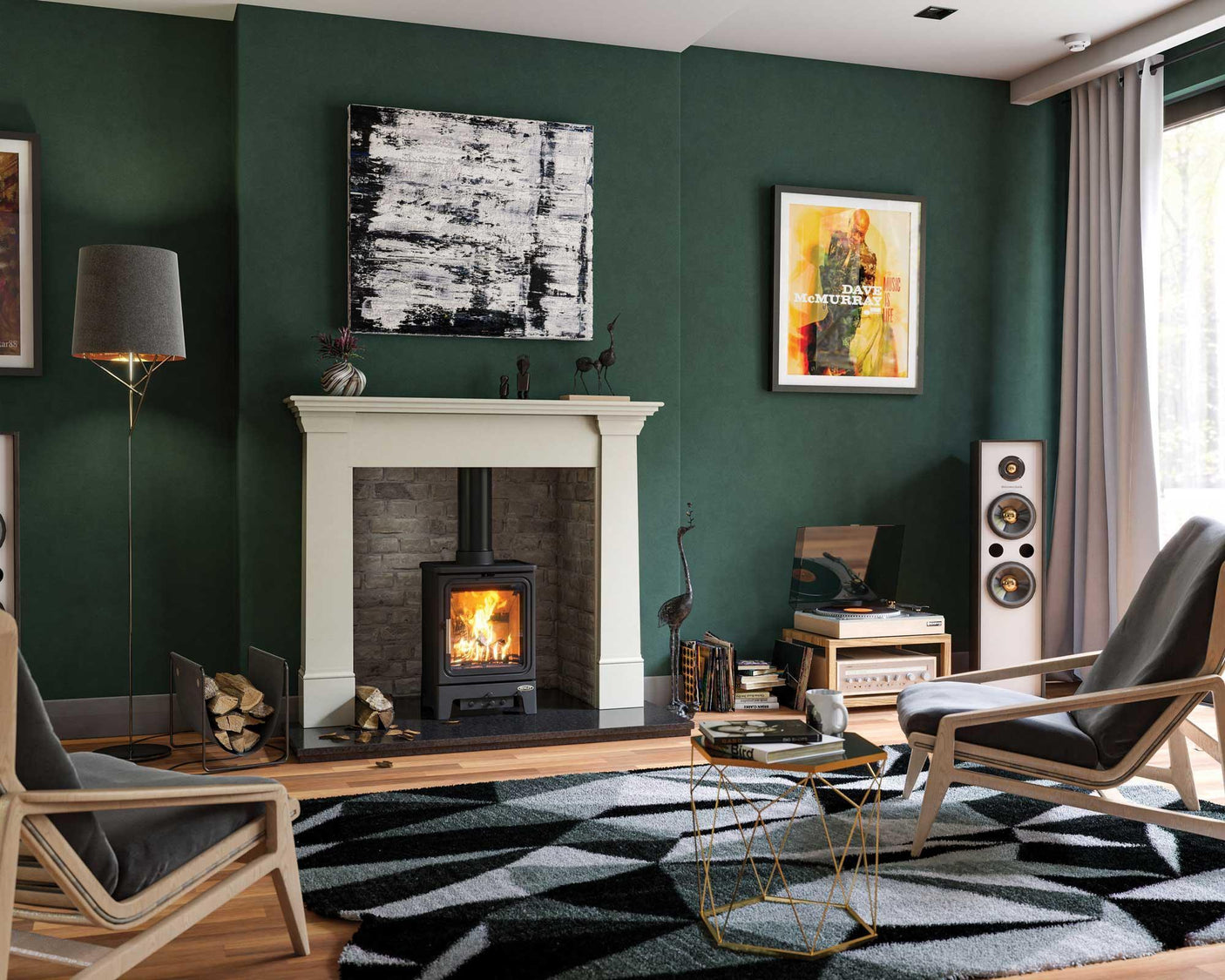 Modern living room with wood burning stove, geometric rug, armchairs, and green walls