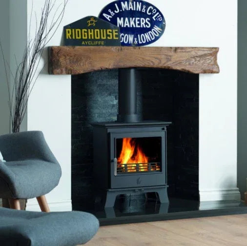 Black wood burning stove with visible flames set in modern fireplace with timber mantel