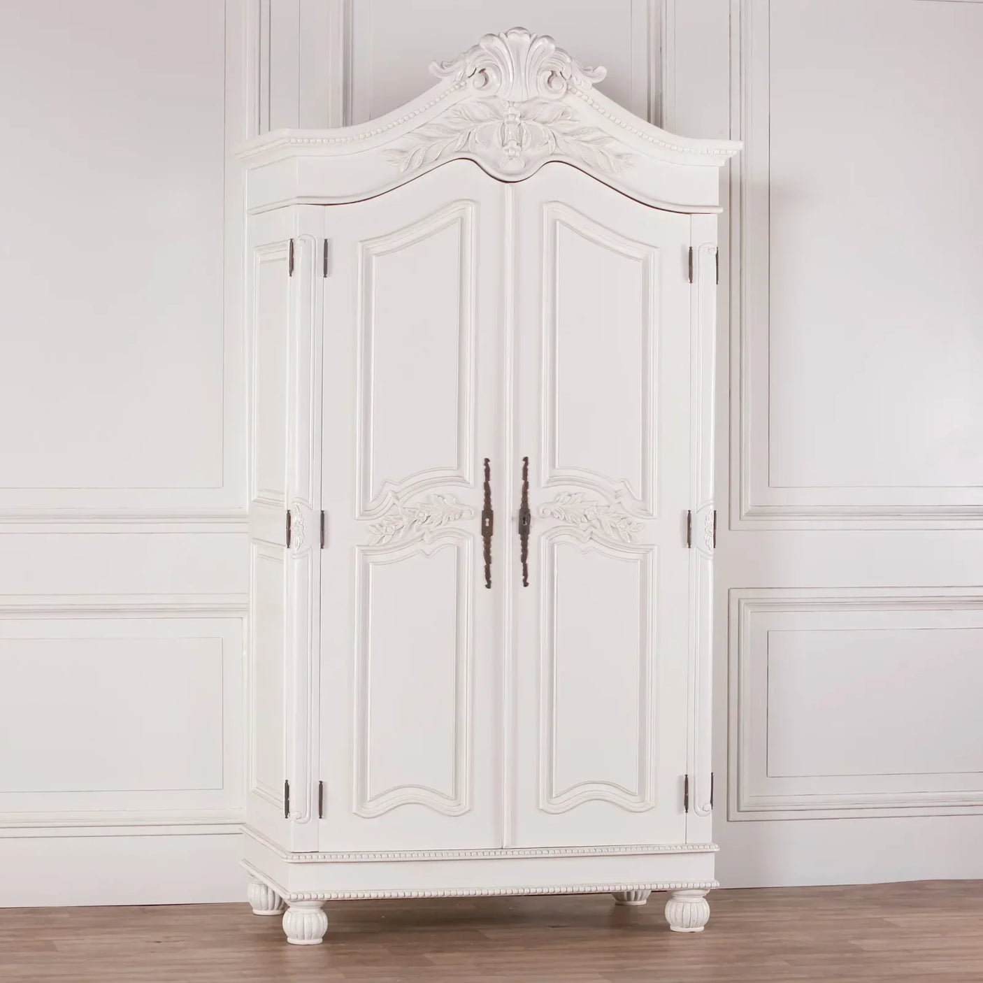 White wooden wardrobe with ornate carved detailing and double doors against panelled wall