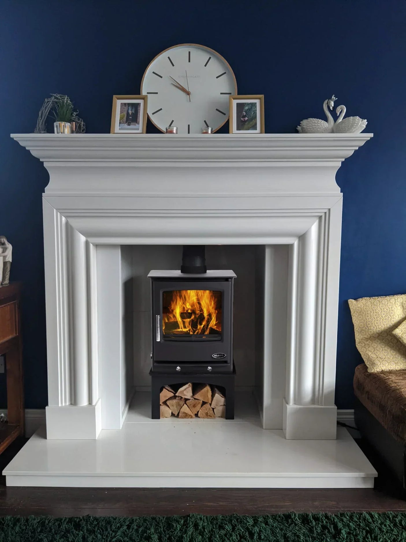 Newport rye wood burning stove with log store set in white fireplace surround