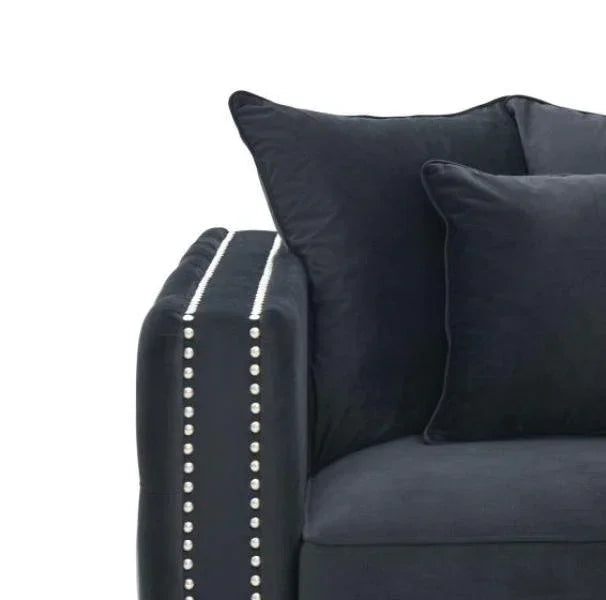 Black velvet sofa corner with studded armrest and matching cushions