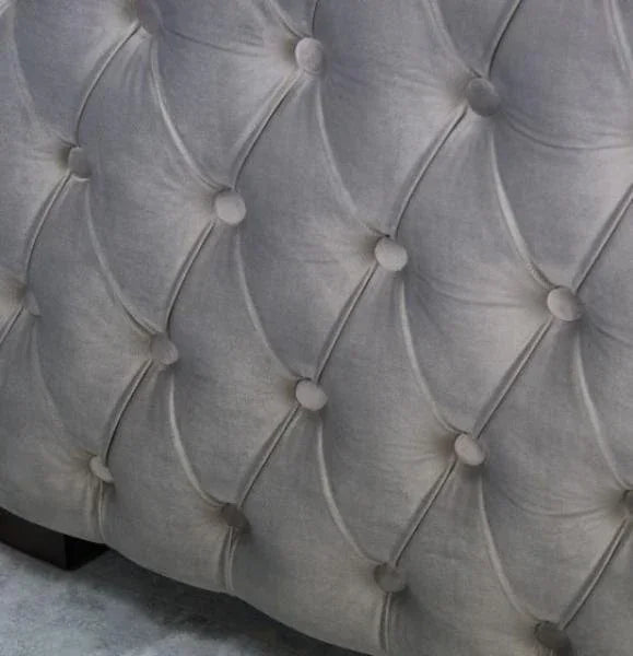 Close up of grey velvet sofa with deep button tufted upholstery
