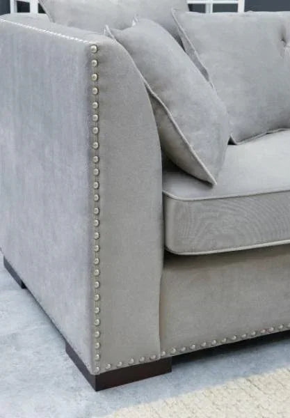 Grey fabric sofa with nailhead trim and matching cushions, close-up of armrest and seat