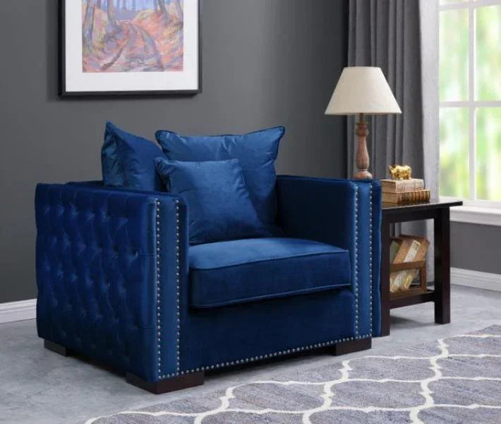 Blue velvet armchair with tufted sides and silver stud detailing beside a wooden side table