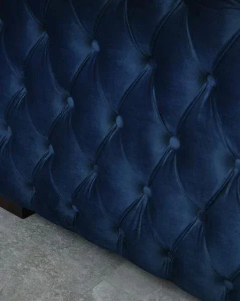 Closeup of navy blue velvet tufted bed frame with button detail on grey floor
