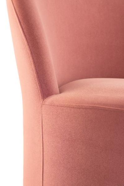 Close-up of pink fabric upholstered chair arm and seat with smooth curved lines