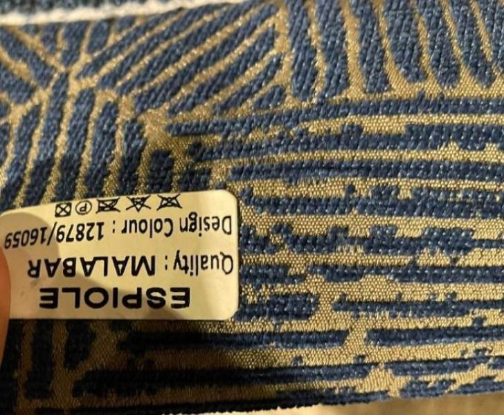 Blue and beige patterned upholstery fabric with care label and design code visible