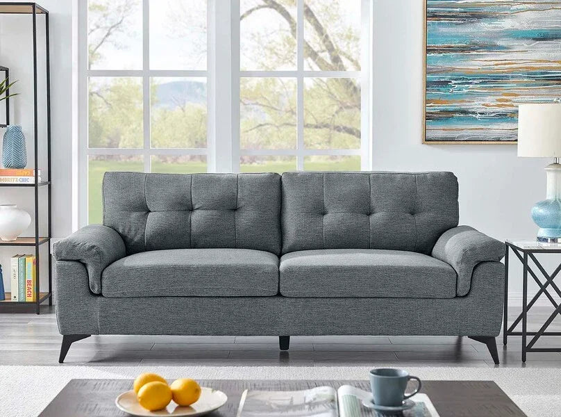 Grey fabric sofa with tufted backrest in modern living room, near large window and side table