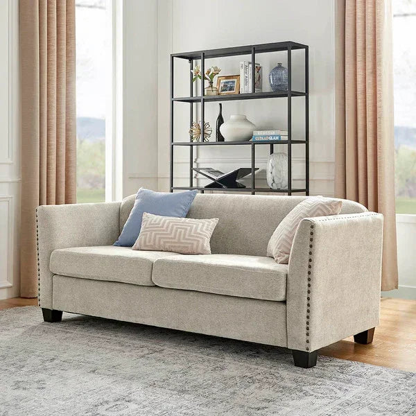 Beige fabric sofa with studded arms and scatter cushions in a modern living room setting
