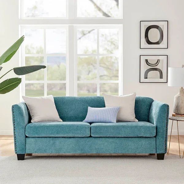 Teal fabric sofa with three cushions in modern living room, large windows in background
