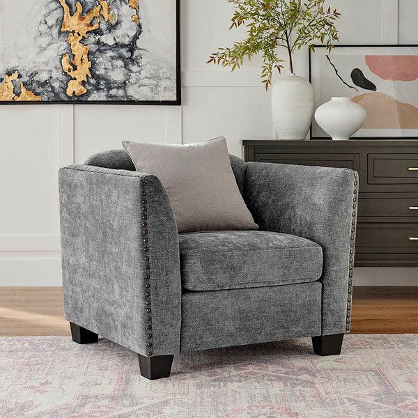 Grey fabric armchair with studded trim and cushion in living room setting