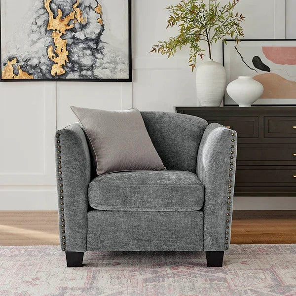 Grey fabric armchair with silver stud detailing and cushion in a stylish living room setting