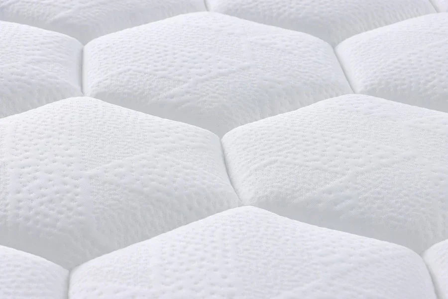 Close-up of white quilted mattress surface with textured hexagonal stitching pattern