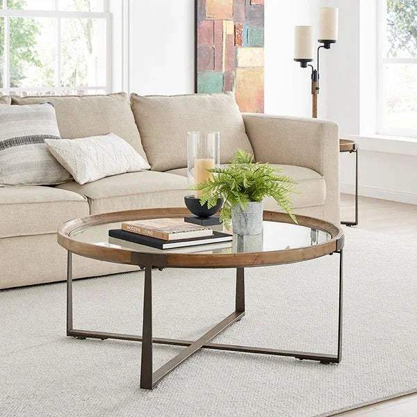 Round glass coffee table with wood trim and metal legs in modern living room