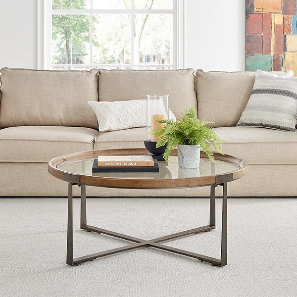 Round glass coffee table with metal frame in front of beige fabric sofa in living room