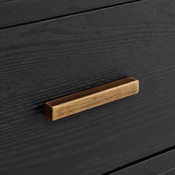 Black wood drawer with rectangular oak handle, close-up of furniture detail