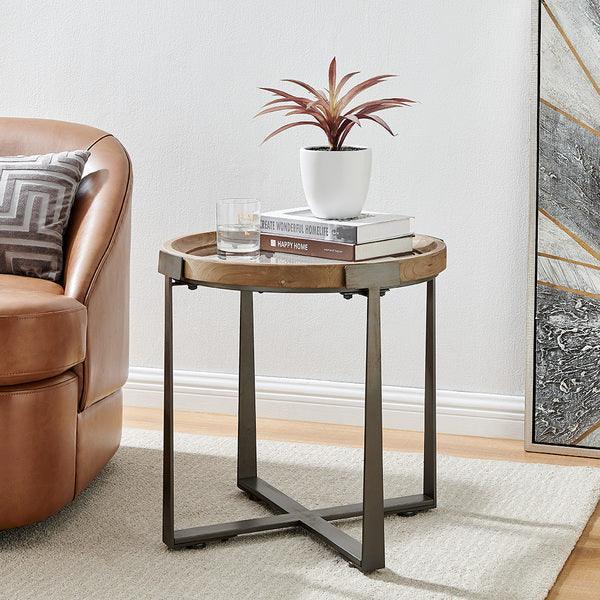 Round wooden side table with metal legs beside tan leather sofa and decorative plant